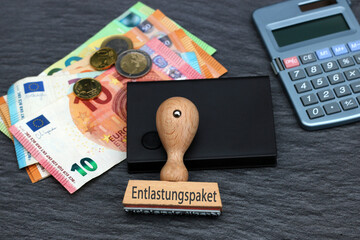 Das Wotr Entlastungspaket auf einem Holzstempel mit Geldscheinen und Taschenrechner. - obrazy, fototapety, plakaty