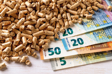 Heap of wood pellets and euro paper banknotes top view. Costs of organic biofuel from compressed...