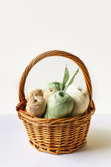 Green and brown yarn threads in a basket for knitting warm clothes with knitting needles, knitting...