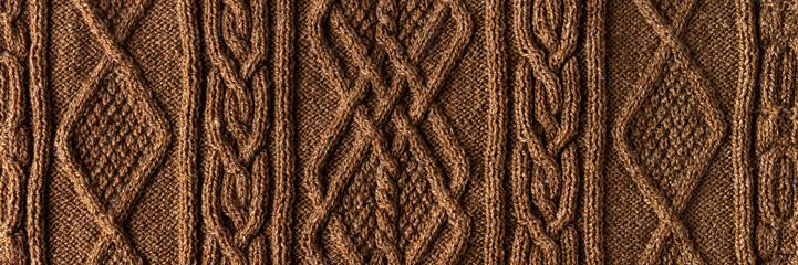 Knitted brown background banner. Large knitted fabric with a pattern. Close-up of a knitted blanket
