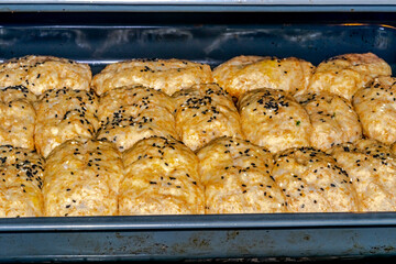 Close up view of homemade bread cooking in the oven tray. Brown yellowish color with black and white sesame seeds.