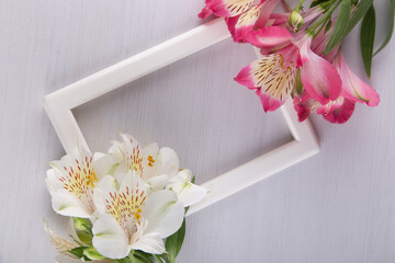Blank photoframe with bright alstroemeria lilly exotic flowers on white background. Flat lay table...