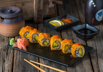 CRUNCHY CALIFORNIA sushi roll served in a cutting board isolated on wooden background side view of...