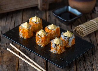CALIFORNIA sushi roll served in a cutting board isolated on wooden background side view of sushi roll