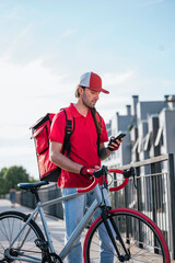 Man who works delivering food by courier at home consulting the smart phone.