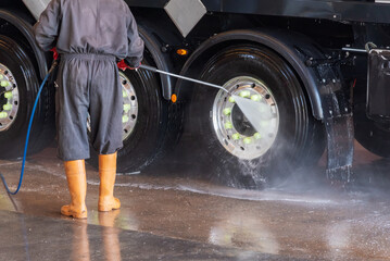 Operator of a truck wash cleaning the tires with pressurized water.