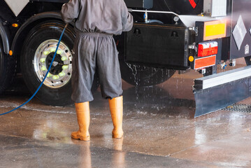 Operator of a truck wash cleaning the trailer with pressurized water.