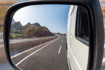 Vision of an angular rearview mirror of a truck traveling on a highway.