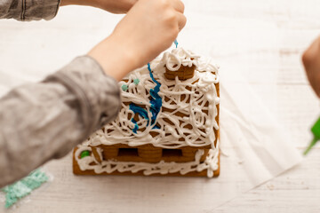 The boy makes a gingerbread house. Preparing for the holiday, creative activity.