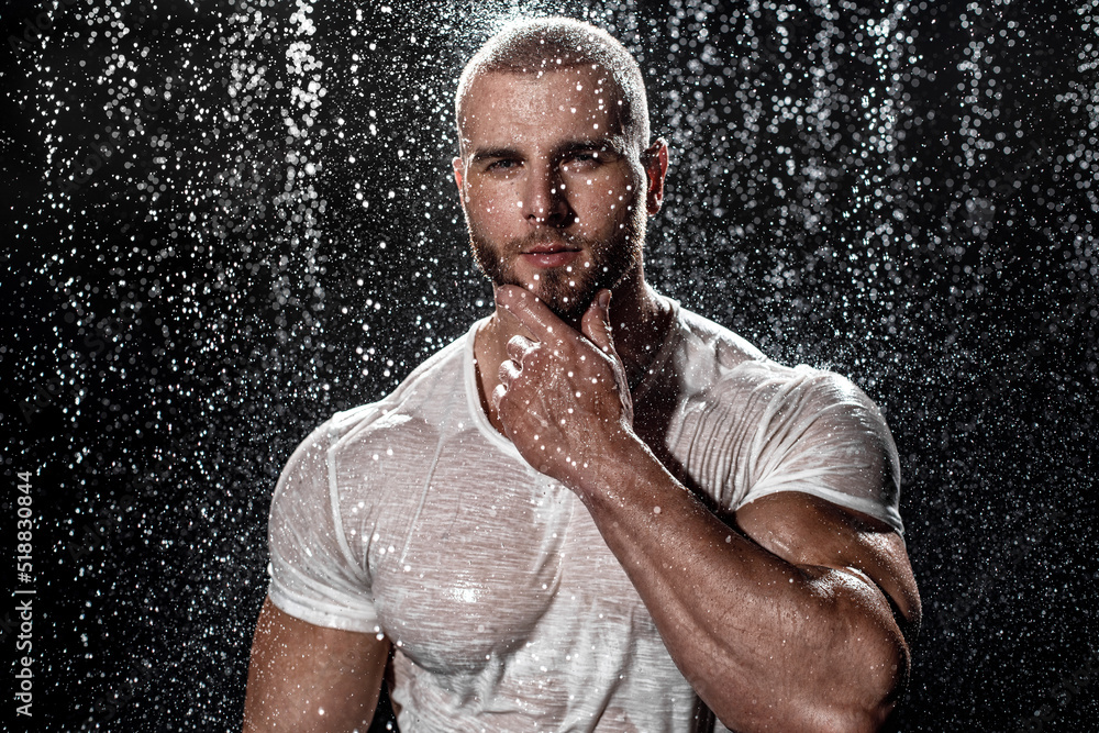 Wall mural Muscular man under the rain in studio. Sexy male in water drops