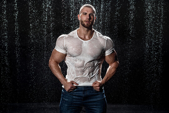 Muscular man under the rain in studio. Sexy male in water drops