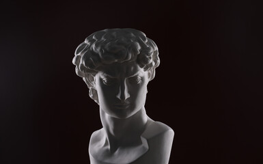 ancient white plaster head sculpture on a black background