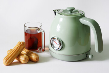 Designer vintage green teapot with a thermometer, next to choux pastries and next to a transparent...
