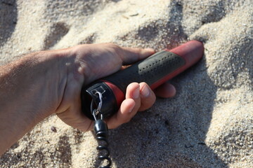 pinpointer in a hand at the beach on the sand