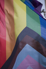 Close Up rainbow gay pride flag outside on a street. Symbol of the Lesbian Bisexual Transgender LGBT community waving in wind against cloudy sky. Social movement for freedom and equliaty. Copy Space