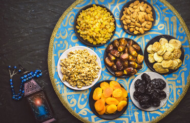 Ramadan celebration. Mix of dried fruits, dates and nuts placed with oriental Ramadan lantern and rosary. Top view with close up. Ramadan background with copy space.