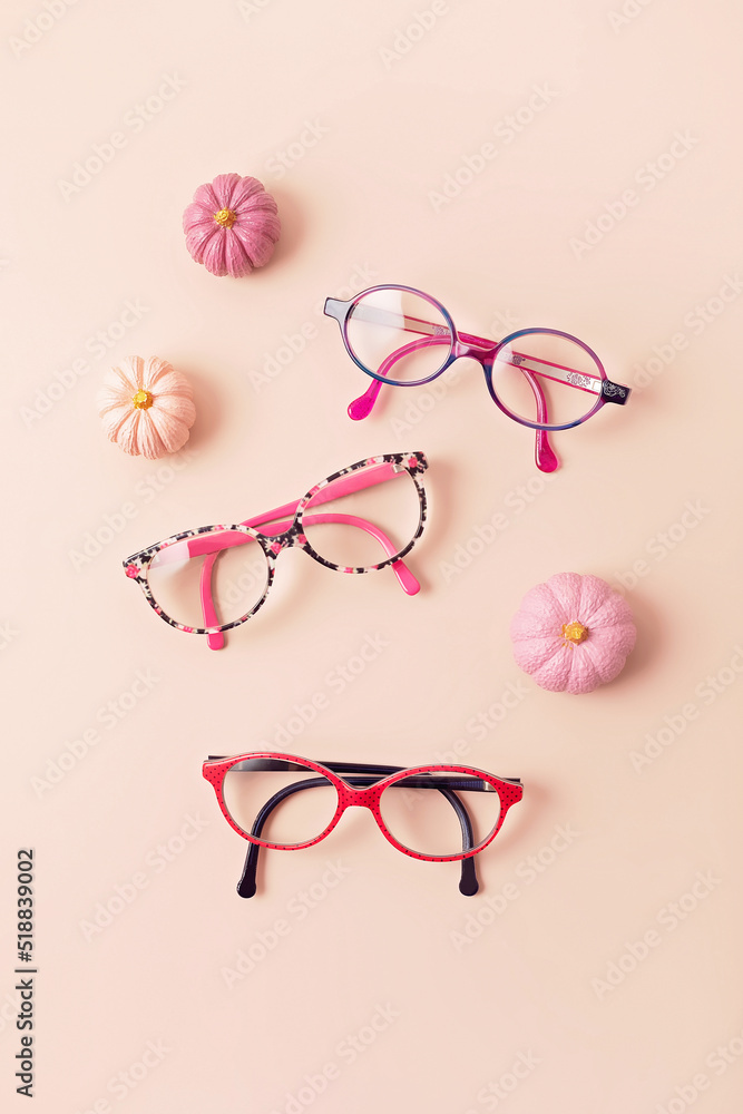 Wall mural Child eyeglasses over pink pastel background. Optical store, glasses selection for kids, eye test, vision examination at optician concept. Top view, flat lay