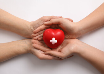 Women holding red heart in hands on white background, top view. Blood donation concept