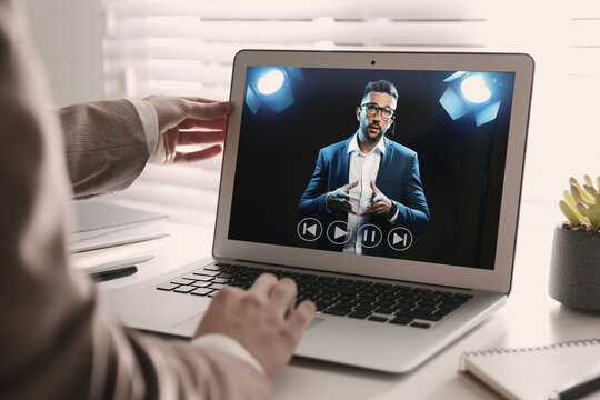 Woman watching performance of motivational speaker on laptop at white table, closeup