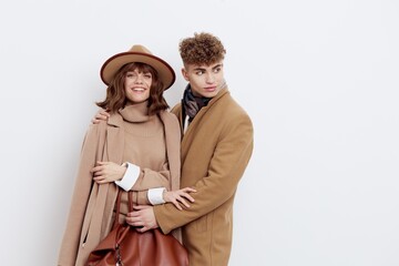 horizontal photo of a sweet, loving couple in autumn clothes standing on a white background gently embracing each other