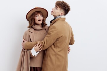 a sweet, beautiful, loving couple stands on a white background in stylish autumn clothes, a woman has a hat on her head, and she gently snuggles up to a man