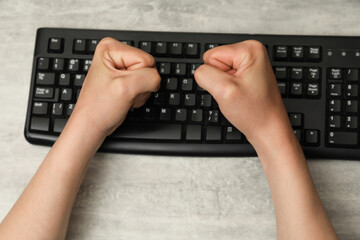 Angry man with clenched fists at table during work, top view