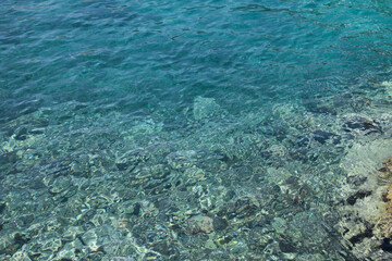 Fototapeta na wymiar Shallow water with rocky sea bottom as background