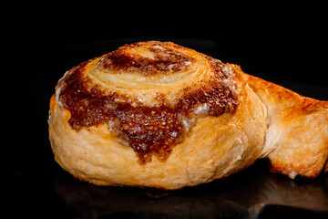 Baked cinnamon bun on tray in electric oven, black background - close up view. Swedish cuisine, homemade bakery, food, cooking and pastry concept