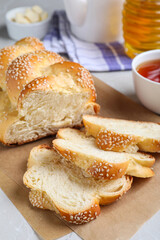 Cut homemade braided bread and freshly brewed tea on light grey table, closeup. Traditional Shabbat challah