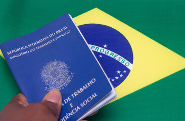 LAURO DE FREITAS, BRASIL - JULY 21, 2022 : hand holding on Brazilian work document with Brazilian flag