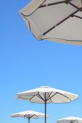 Beautiful white beach umbrellas against blue sky