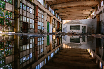 Inside of flooded dirty abandoned ruined industrial building with water reflection