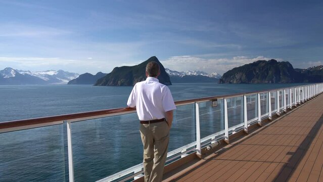 Senior adult man alone on deck of cruise ship leaving Alaskan port of Seward