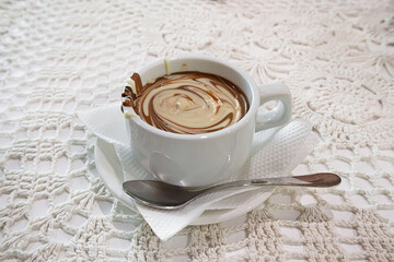 Hot homemade white and dark chocolate in a white mug. Knitted tablecloth. Dessert
