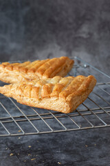 Apple turnover, freshly cooked, cooling down on a metal cooling rack. On a dark stone background