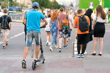 A man on an electric scooter crossing street in the crowd. Crosswalk. Alternative. Eco....