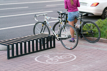 An empty rectangular metallic rack used to hold bicycles on the sidewalk with standing bicycles and...