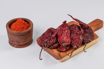 Capsicum baccatum, red chili pods and red chili powder on white table