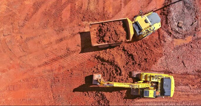 Construction site preparation work with an excavator loading earth into dump trucks