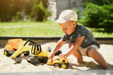 Child playing in sandbox. Little boy having fun on playground in sandpit. Outdoor creative activities for kids. Summer and childhood concept
