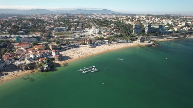 Aerial view of Duquesa Beach in Cascais, Portugal during the summer. People playing in the inflatable water park
