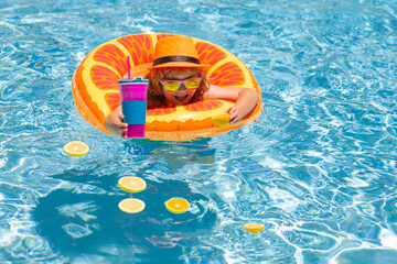 Summer kids cocktail. Happy little boy with colorful inflatable ring in swimming pool. Child splashing in swimming pool. Swim water sport activity on summer vacation with child. Kids water toys.