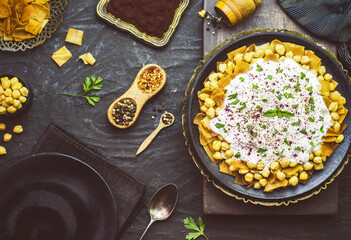 Arabic Cuisine; Lebanese authentic "Fattah" or" Fatteh" with toasted pita bread, chickpeas and yogurt sauce on rustic dark background. 