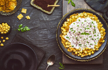 Arabic Cuisine; Lebanese authentic "Fattah" or" Fatteh" with toasted pita bread, chickpeas and yogurt sauce on rustic dark background. Close-up with copy space.
