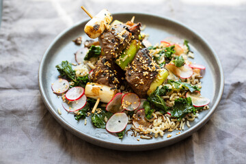 Beef steak skewers with rice, kale and radishes