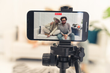 Video recording of two beloved white people sitting on the sofa done by the use of smart phone - closeup studio shoot. High quality photo