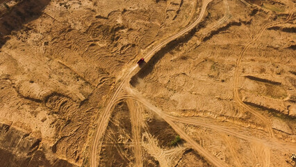 Top view of dusty sandy dirt road with wheels tracks and driving red truck. Scene. Truck moving and...