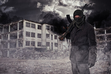 armed masked soldier in front of destroyed building. guerrilla warfare concept.