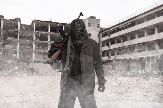 Armed Masked Soldier In Front Of Destroyed Building. Guerrilla Warfare Concept.