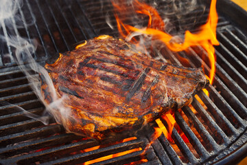Barbecue dry aged Wagyu cote de boeuf steak grilled as close-up on a charcoal grill with fire and...